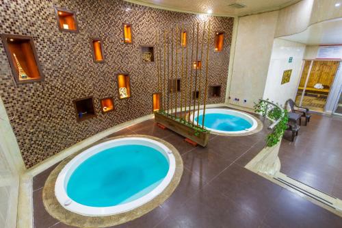 波哥大Tequendama Suites Bogota的两个浴池,位于酒店,设有两个蓝色的游泳池