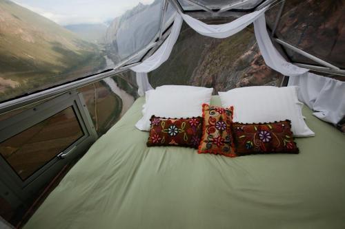 乌鲁班巴冒险套房天空旅馆的山顶上带枕头的床
