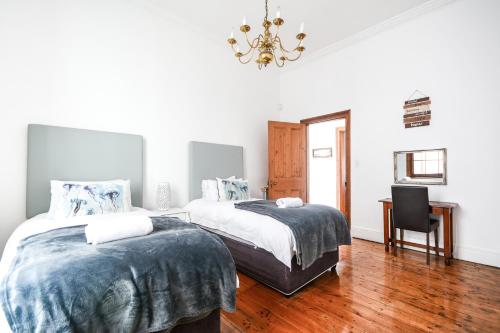 梅森堡Oceanfront Penthouse的一间卧室配有两张床、一张书桌和一个吊灯。