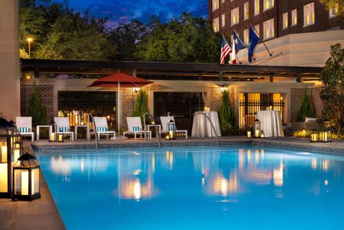 达拉斯华威梅尔罗斯酒店的一个带桌椅的夜间游泳池