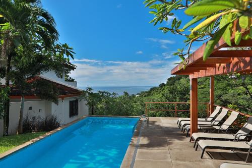 蒙特苏马素馨别墅的一个带椅子的游泳池,背景是大海