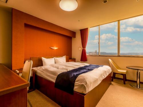 加贺Yukai Resort Saichoraku的酒店客房设有一张床、一张书桌和窗户。