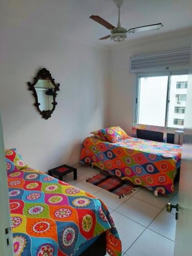 瓜鲁雅Apto pé na areia Praia das Pitangueiras - Centro的一间卧室配有两张床和吊扇