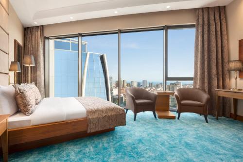 伊斯坦布尔Days Hotel by Wyndham Istanbul Maltepe的酒店客房设有床、椅子和大窗户。