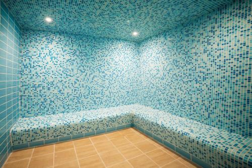 吉达Swiss Blue Hotel Hera的浴室设有蓝色瓷砖墙壁和长凳