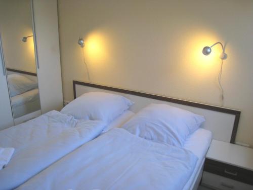 斯塔贝多福Fehmarnstrand 78 App 14的一间卧室配有两张床,墙上有两盏灯