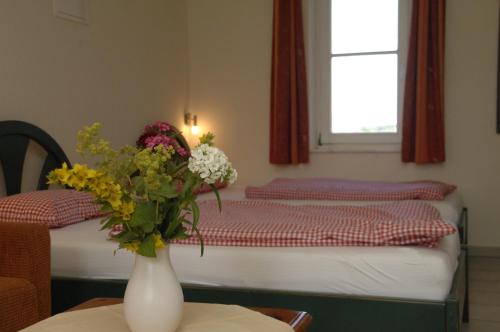 Neu KlockenhagenMaisonette-Ferienwohnung "Trakehnen"的一间设有两张床的房间和一个花瓶,摆放在桌子上