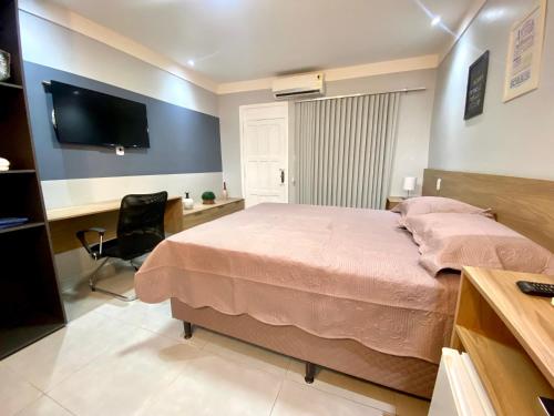 马卡帕Apartamento Studio Centro de Macapá的一间卧室配有一张床、一张书桌和一台电视