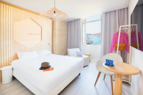 马赛Hôtel Life Marseille VP - Vieux Port的酒店客房,配有一张床和一张桌子上的帽子