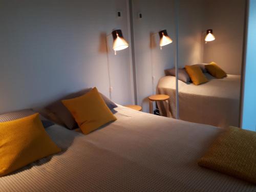汉科Graniitti的一间卧室配有两张带黄色枕头和镜子的床