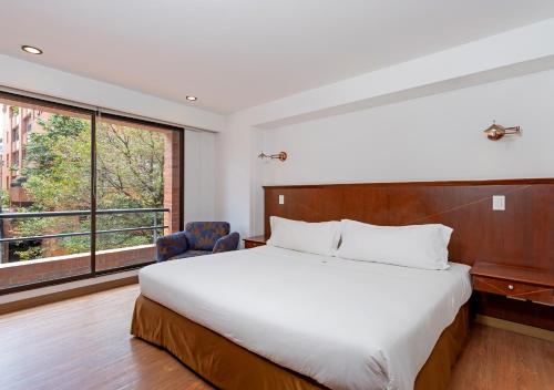 波哥大GIO Suites Parque 93 Bogotá的一间卧室设有一张大床和一个大窗户