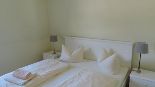 奥茨塞巴德·迪尔哈根Akazienhaus 6的一张带枕头和毛巾的白色床