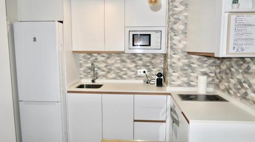 塞维利亚Sevilla Alameda PG Apartamentos的白色的厨房配有水槽和微波炉