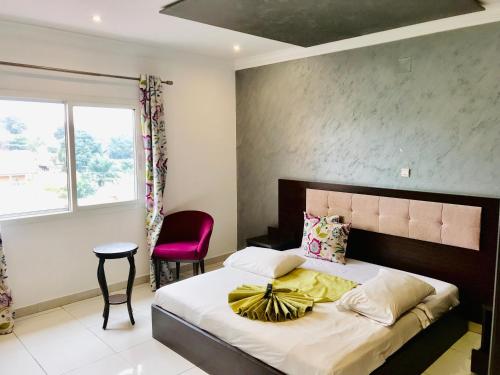 布拉柴维尔Capital Hôtel的一间卧室配有一张大床和一张红色椅子