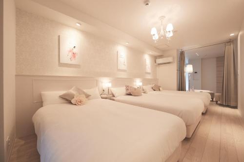 松户市ReLA Higashimatsudo - Vacation STAY 66996v的客房设有三张床、白色床单和吊灯。