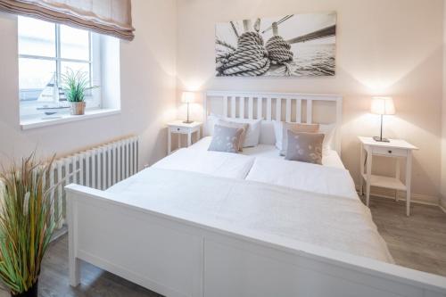 WestermarkelsdorfAusternfischer的白色卧室配有一张白色的大床和两张桌子