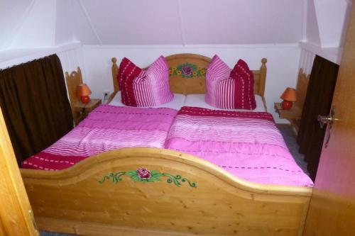 坡瑟利特兹Heublein的一间卧室配有一张带粉色床单和枕头的木床。