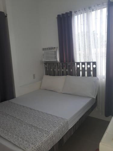塔比拉兰戈麦斯公寓的一张带白色床单和枕头的床,位于窗户前