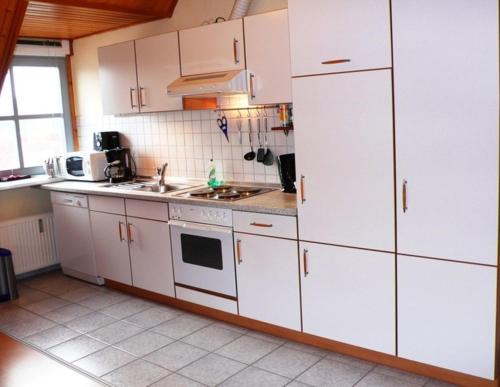 奥斯特巴德里克Ferienwohnung "Uferschwalbe"的厨房配有白色橱柜和水槽
