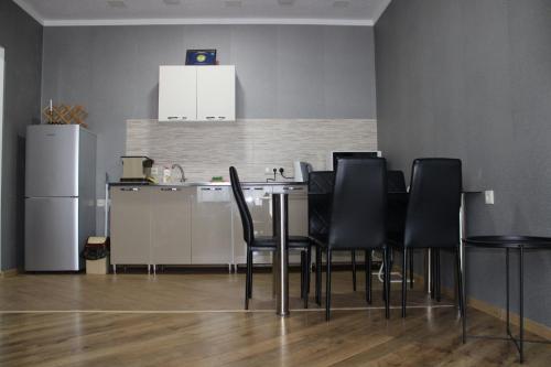 第比利斯Ann's Apartment的厨房配有带黑色椅子的桌子和冰箱。