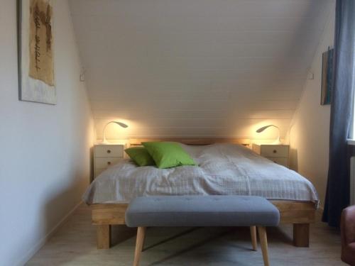 Neue Tiefe FehmarnFerienhaus an der Buche - 72952的一间卧室配有一张带绿色枕头和两盏灯的床