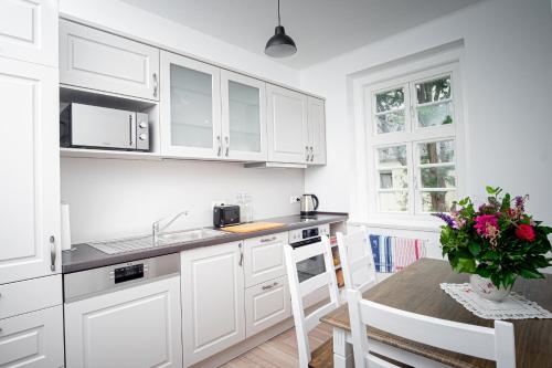 戈斯拉尔Altstadt Apartment的厨房配有白色橱柜和花瓶桌子