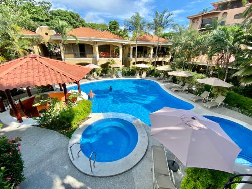雅科蒙特卡罗豪华公寓酒店的度假村的游泳池配有遮阳伞和椅子