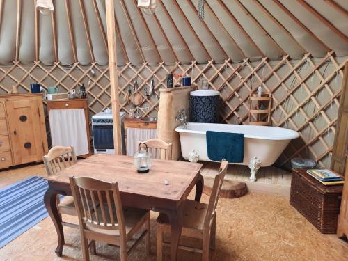 XhorisLa yourte au fonds du jardin的圆顶帐篷配有木桌和浴缸