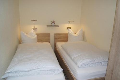 费曼城堡Ferienwohnung Glöckner的小客房内的两张床,配有白色床单