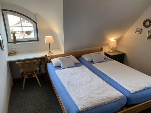 博恩Ferienwohnung Nr 02 OG Spitzboden的一间卧室设有两张床、一张桌子和一个窗口。
