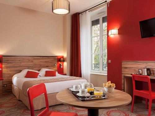 里昂Aparthotel Adagio Lyon Patio Confluence的一间酒店客房,配有一张床铺和一张桌子,并提供一个食品托盘