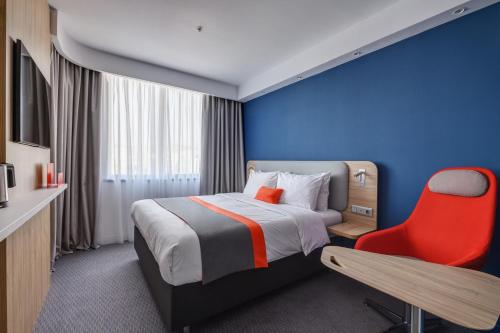 阿拉木图Holiday Inn Express - Almaty, an IHG Hotel的酒店客房,配有一张床和一张红色椅子