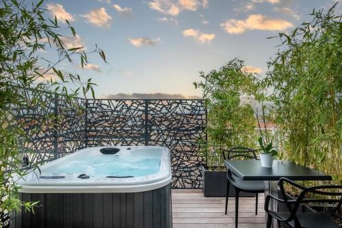波尔多Le Boutique Hotel & Spa的甲板上的热水浴池配有桌椅
