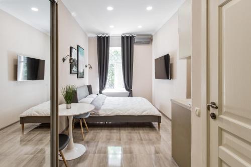 敖德萨Havana ApartHotel的一间卧室配有一张床、一张桌子和一个窗户。