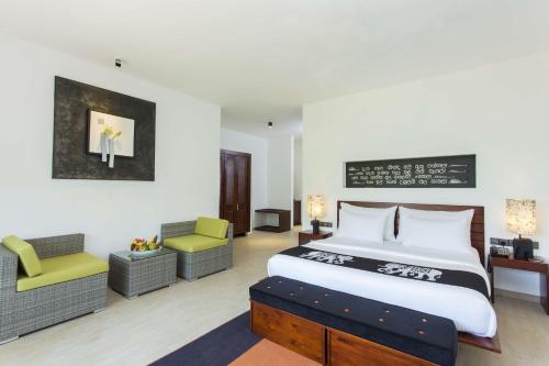 锡吉里亚Aliya Resort and Spa - Thema Collection的一间卧室配有一张大床和两把椅子