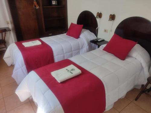 科洛尼亚-德尔萨克拉门托罗米酒店的酒店客房带两张红色和白色的床单