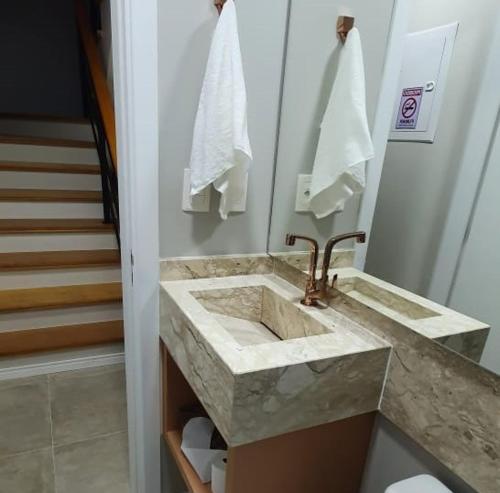 卡内拉Casa Nova Canela Condominio Fechado 40的一间带大理石盥洗盆和楼梯的浴室