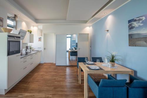 费曼城堡Strandburg Azurblau的厨房以及带桌子和蓝色椅子的用餐室。