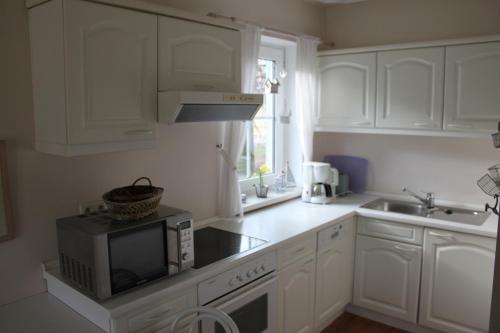 奥茨塞巴德·迪尔哈根"Achtern Diek" Doppelhaushälfte的白色的厨房配有微波炉和水槽