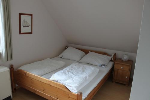 奥茨塞巴德·迪尔哈根"Achtern Diek" Doppelhaushälfte的一张带白色床单和枕头的床