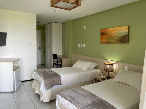 巴雷里尼亚斯Barreirinhas Lençóis Flat Residence的酒店客房设有两张床和一张桌子。
