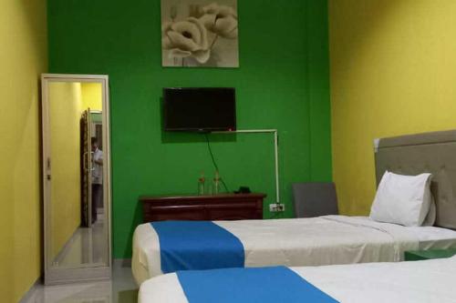 TjolomaduRedDoorz near Bandara Adi Soemarmo Solo的一间卧室设有两张床和绿色的墙壁