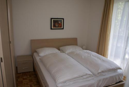 巴德小基希海姆Appartementanlage Bach的窗户客房内的一张带白色枕头的床