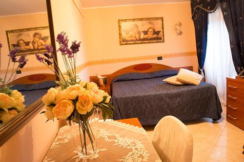 阿尔巴诺拉齐亚莱阿尔缇耶利别墅酒店的一间卧室配有一张床和一张花瓶桌子