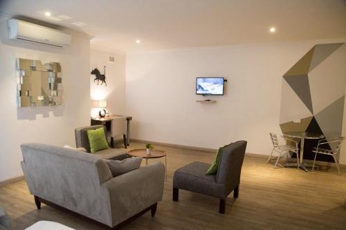 卢萨卡cairo apartment的客厅配有两把椅子和墙上的电视