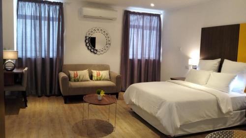 卢萨卡cairo apartment的一间卧室配有一张床、一张沙发和一把椅子