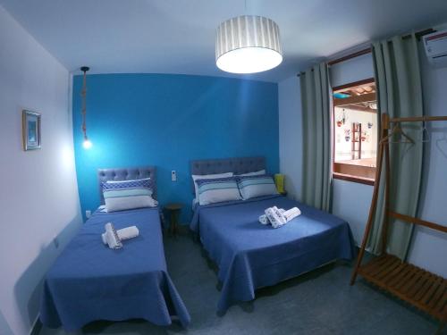 卡波布里奥Pousada Melodia do Mar的蓝色的客房设有两张床和窗户。