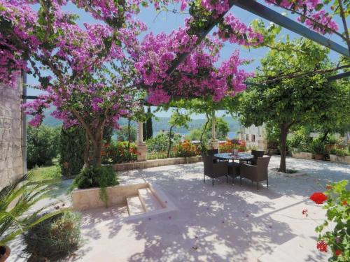斯拉诺Apartments & Room Eva Slano的天井设有桌子和紫色的花卉树木