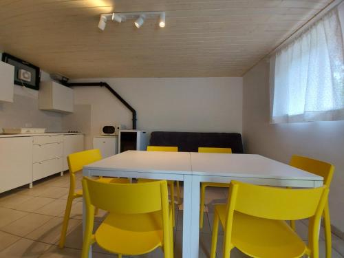 KomenApartmaji Hedera的厨房配有白色的桌子和黄色的椅子