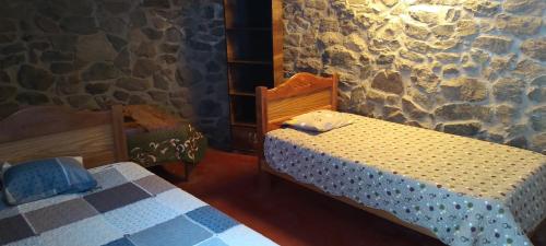 卡瓦纳科德Casa De Virginia的一间卧室设有两张床和石墙